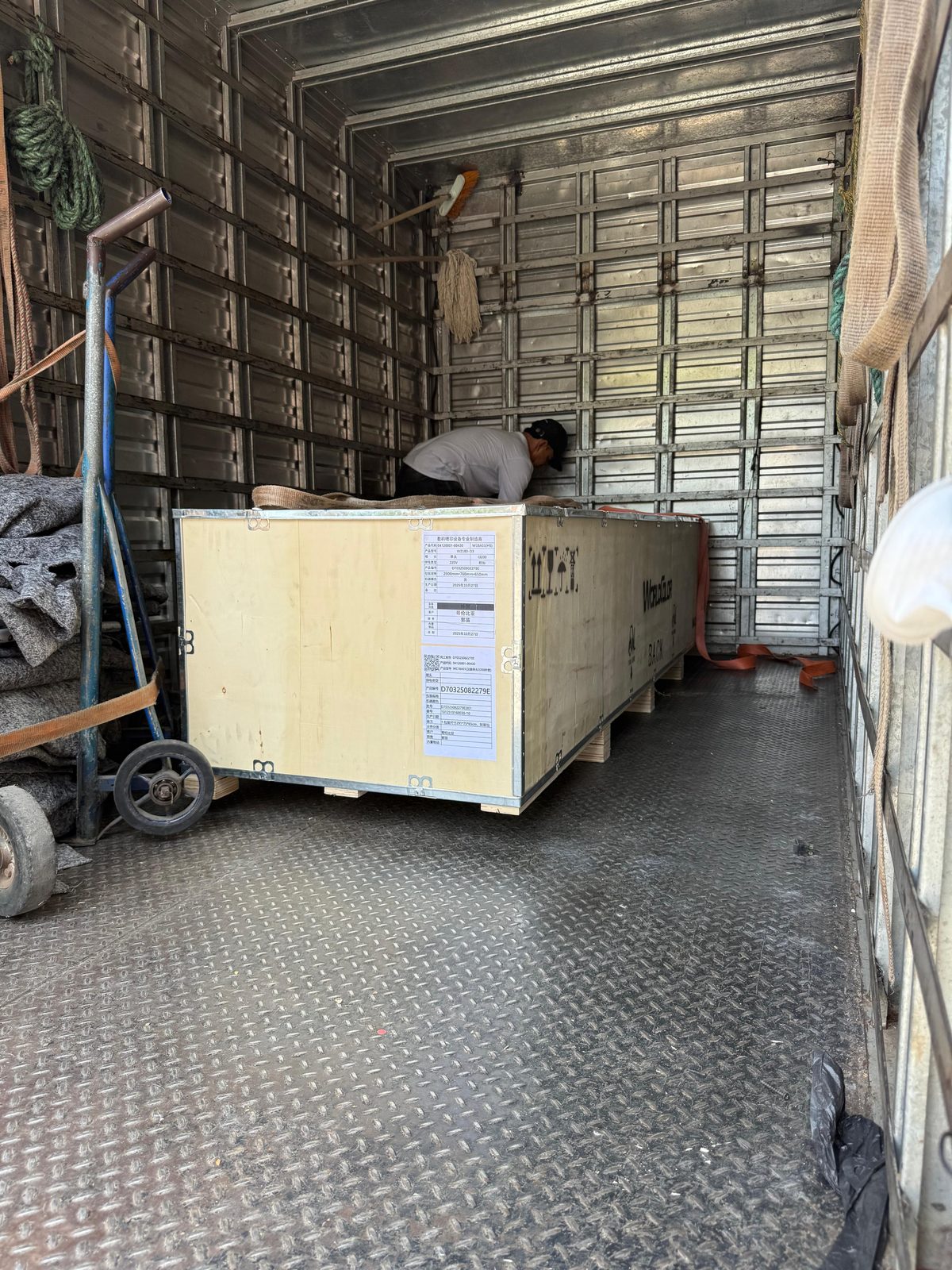 Cajón con máquina industrial siendo cargado en camión en China para su exportación a Colombia